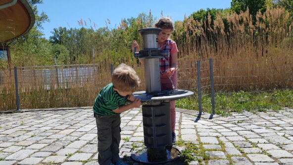 Kinder trinken am Trinkbrunnen