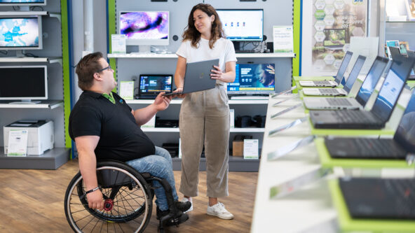 Mann im Rollstuhl und Frau mit Laptop in der Hand in einem afb-Shop