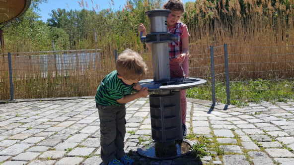 Kinder trinken am Trinkbrunnen